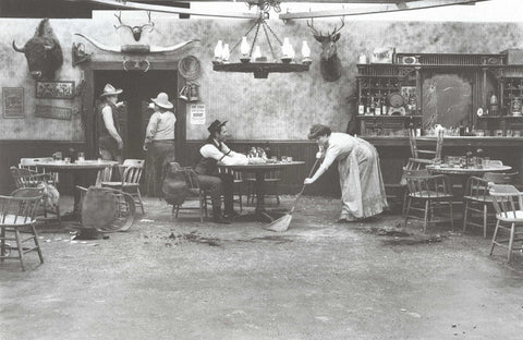 Woman sweeping saloon floor with cowboys (black & white)